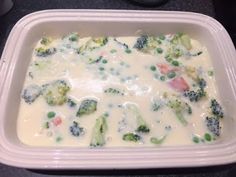 a casserole dish with broccoli and peas in it on a table