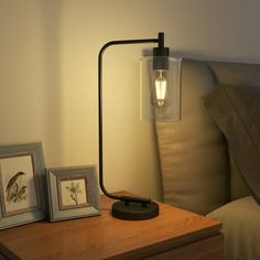 a lamp on a night stand next to two pictures