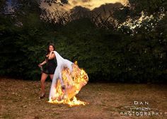 a woman standing in front of a fire with her arms around the back of her body