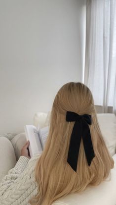 a woman with long blonde hair wearing a black bow