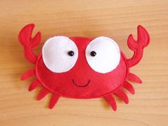 a close up of a red crab on a wooden surface with white eyes and one black eye