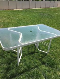 a table that is in the grass with some water on it's top and bottom