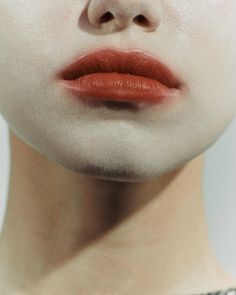 a woman's face with red lipstick and white makeup on the upper half of her face