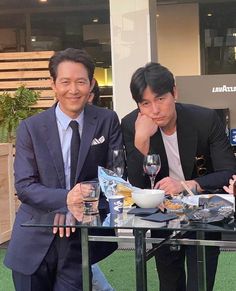 three men sitting at a table with food and drinks