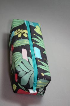 "This handmade bag can be used either as a cosmetic bag for on the go, or even a pencil pouch. It's made with an prickly print of succulents and cacti on a grey/gray background which is made of cotton fabric. The inside is lined with salmon pink cotton fabric. I've also used a natural cotton batting, for quilting, to make for a sturdier bag. And has a coordinating aqua zipper. Placement of print may vary. Here are just a few ways to use this bag: Makeup Hair accessories Pencil Case On-the-go Sew Green Zippered Pencil Case, Green Cosmetic Bag With Pen Holders For Everyday Use, Rectangular Green Pencil Case, Large Succulents, Zipper Pencil Pouch, Pink Cotton Fabric, Bag Makeup, Cactus Print, Handmade Bag