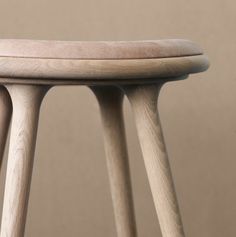 a wooden stool sitting on top of a hard wood floor next to a brown wall