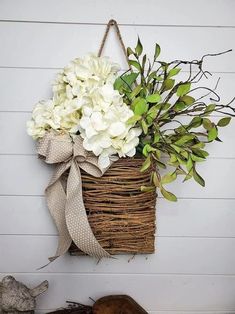 a basket filled with white flowers hanging on a wall next to a stuffed animal and plant