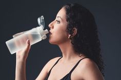 a woman is drinking from a plastic bottle