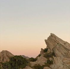 a large rock outcropping in the middle of a desert area at sunset