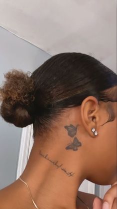 the back of a woman's head with a butterfly tattoo on her left side