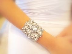 a close up of a person wearing a wedding dress and holding a bracelet with jewels on it