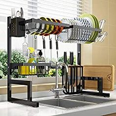 the kitchen sink is filled with dishes and utensils in black racks, hanging from the wall