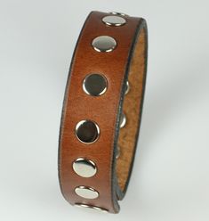 a brown leather bracelet with metal studs on the side and two holes in the middle