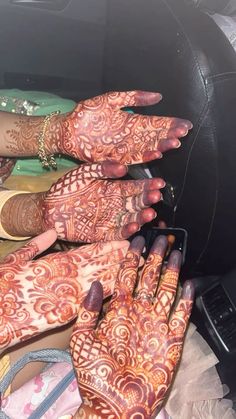 two hands with henna designs on them sitting in the back seat of a car