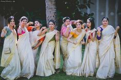 a group of women standing next to each other wearing sari's and holding their hands in the air