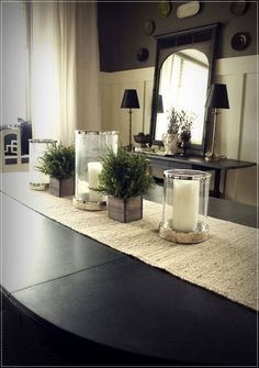 candles and plants on a table with a mirror in the background