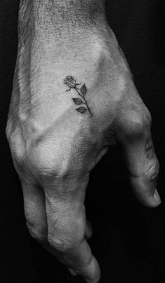 a small rose tattoo on the left side of the hand is shown in black and white