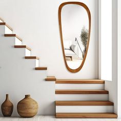 there is a mirror on the wall next to some vases and a stair case