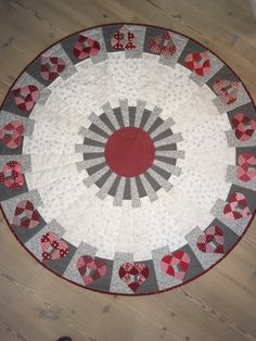 a red and white quilted table top on a wooden floor next to a pair of shoes