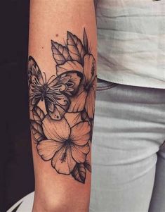 a woman's arm with a butterfly and flowers tattoo on the left side of her arm