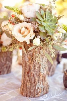 two vases filled with flowers sitting on top of a white tablecloth covered table