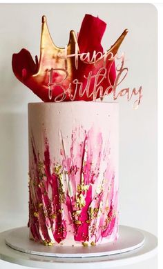 a birthday cake decorated with pink and gold icing on top of a white table