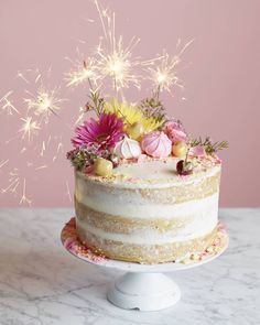 a white cake with flowers and sparklers on top