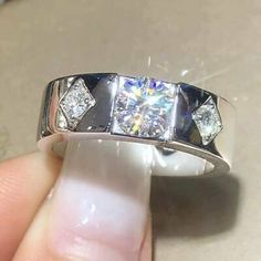 someone is holding their wedding ring with three diamonds on the top and bottom half of it