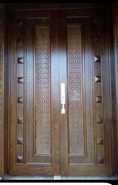 two wooden doors with intricate carvings on them in front of a wall and door frame