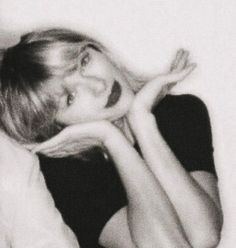 a black and white photo of a woman laying on her side with her hands behind her head