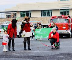 people in costumes are walking their dogs through the parking lot with firetrucks behind them