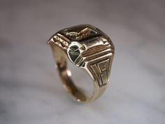 Herff Jones Art Deco style 10k yellow gold ring is size 7. Band tapers from 15mm to 3mm with beveled plaque on top. Plaque design consists of a shield with the name of the school engraved on it, which is too worn to see. Bevels are decorated with geometric patterns and engraved with the letters D and J. The sides of the ring have the numbers 19 and 36 incised into them, all in a high polish finish. Stamped HJ.CO SUPERTONE PATENTED. 14k Gold Art Deco Signet Ring With Polished Finish, Gold Art Deco Engraved Ring, Art Deco Gold Signet Ring With Polished Finish, Art Deco Polished Signet Ring As Gift, Collectible Art Deco Signet Ring With Polished Finish, Art Deco Gold Engraved Ring, Art Deco Engraved Gold Ring, Art Deco Engraved Signet Ring, Herff Jones