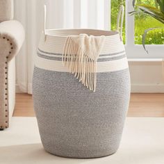 a large gray and white basket sitting on top of a rug next to a window