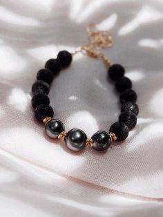 Adorned with a mix of textured lava beads and a trio of black Tahitian pearls, this handcrafted Hawaiian stacking bracelet is a stylish personification of Hawaii’s enigmatic allure. This stunning Tahitian pearl bracelet elegantly exemplifies mindful island living. Wear this beaded bracelet alone or stacked for a classically elegant statement.✦ DETAILS ✦✧ Name: Kalani (ka LA nee) - the heavens, sky, royal one.✧ Adjustable Length from: 7"-8.5".✧ 3 Genuine Tahitian Pearls 8-10mm AA-AAA quality; sha Elegant Lava Stone Beaded Bracelets, Elegant Lava Stone Bracelets With Round Beads, Elegant Lava Stone Bracelet With Round Beads, Elegant Adjustable Lava Stone Jewelry, Lava Stone Beaded Bracelet Jewelry, Black Beaded Lava Stone Jewelry, Black Beads Lava Stone Jewelry, Elegant Black Lava Stone Beaded Bracelets, Elegant Black Lava Stone Jewelry