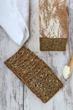 two slices of bread and a spoon on a white wooden table next to each other