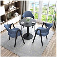 a dining room table with four chairs and a rug in front of a window overlooking the ocean