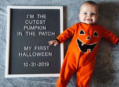 a baby wearing an orange pumpkin costume next to a sign that says i'm the cutest pumpkin in the patch