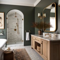 a large bathroom with green walls and marble counter tops, gold accents on the shower