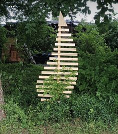 a sculpture made out of wooden sticks in the middle of a field next to a tree