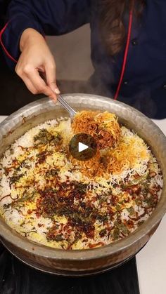 a person scooping food out of a large pan