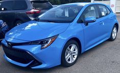 a blue car parked in a parking lot next to other cars