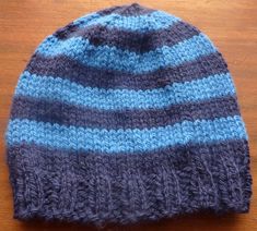 a blue and gray knitted hat sitting on top of a wooden table