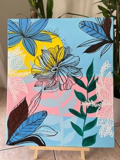 a painting on a wooden easel with flowers and leaves painted on the canvass