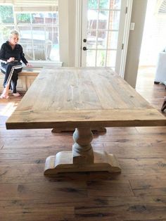 a woman sitting at a wooden table in a living room