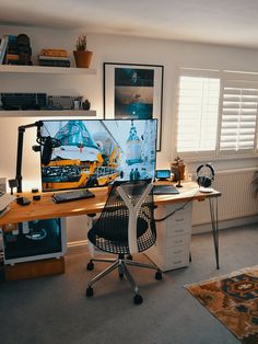 a desk with a computer monitor and keyboard on it in front of a window filled with books