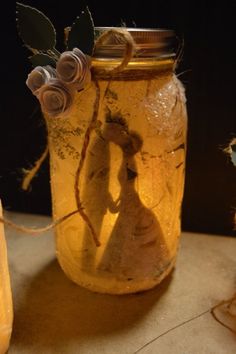 a glass jar filled with flowers and twine on top of a table next to a candle