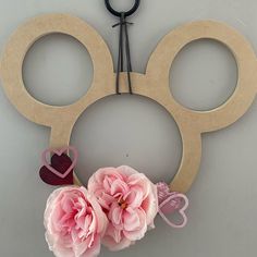 a pair of scissors and some pink flowers on a gray surface with two hearts attached to it