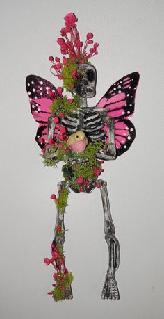 a skeleton with flowers and a stuffed animal in the shape of a butterfly on it's back