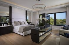 a bedroom with a large bed and two couches in front of windows overlooking the water