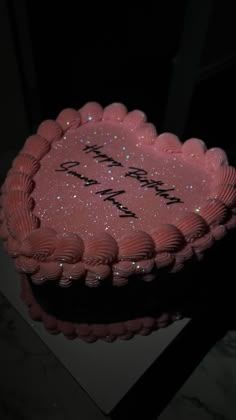 a pink heart shaped cake with the words happy birthday written on it in black lettering